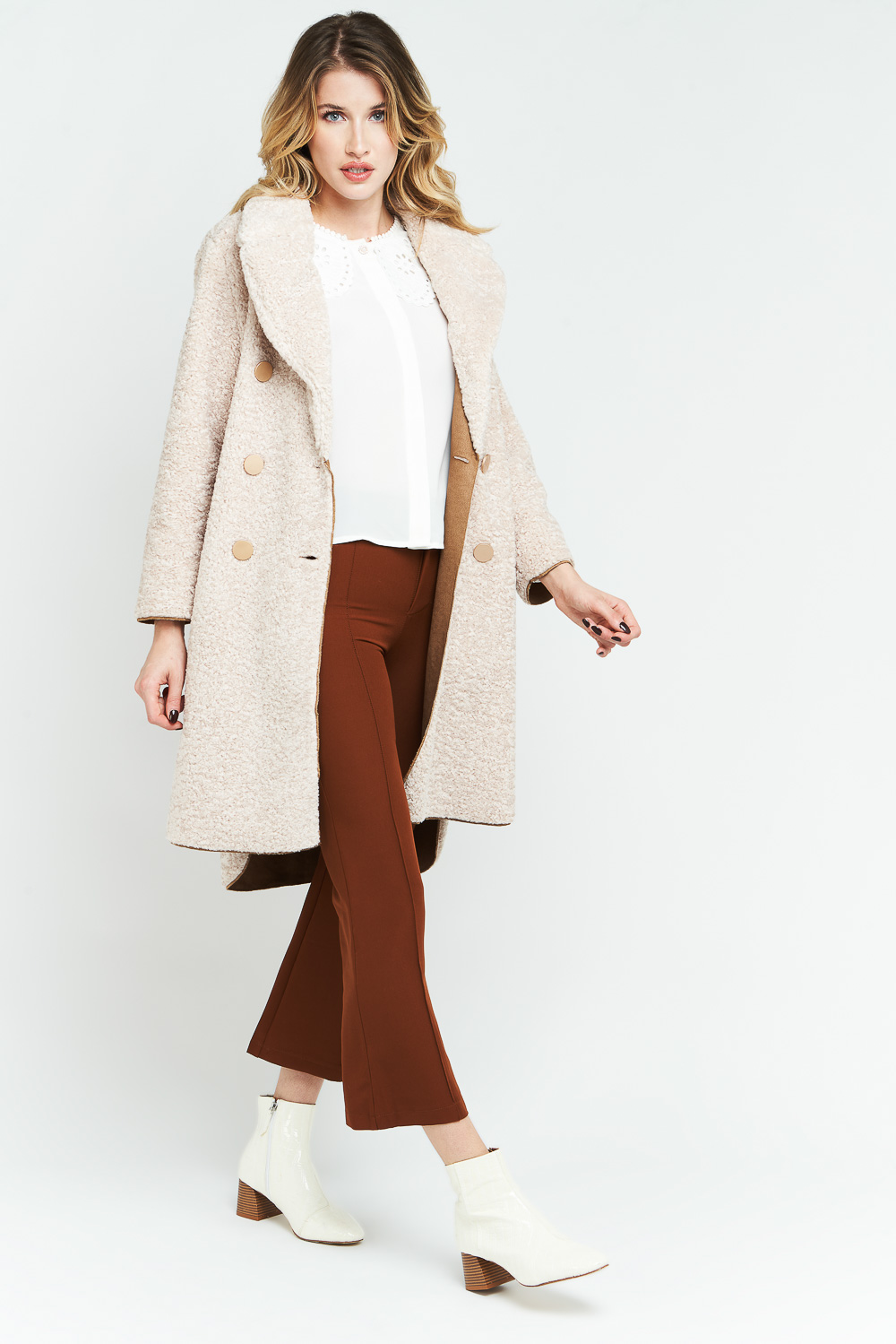 Femme en manteau long pantalon marron sur fond gris