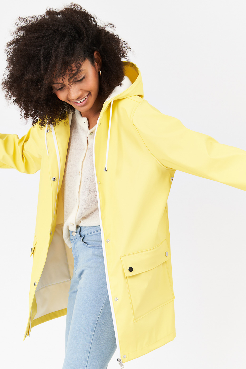 Lookbook d'une femme en manteau jaune et pantalon bleu sur fond gris